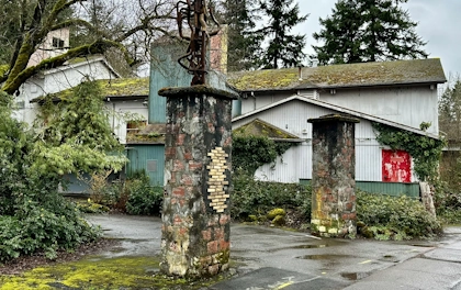 An old building with stone entryway pillars and moss covered roof