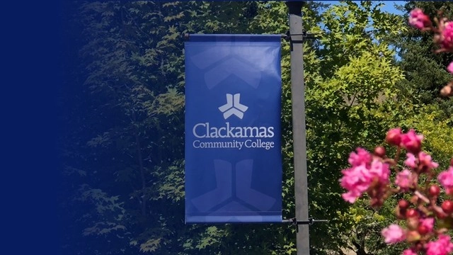 CCC logo banner attached to a post outside surrounded by flowers